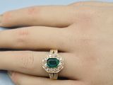 an image of a woman ' s hand with a gold ring with a green stone