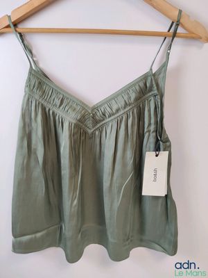 the back of a green top hanging on a wooden hanger