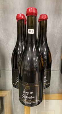 Trois bouteilles de vin sont exposées dans une vitrine.