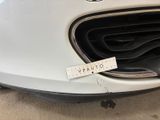 the front bumper of a white car with a sticker on it