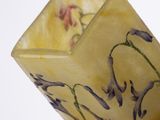someone is holding a yellow vase with purple flowers in it
