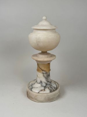 a white marble pedestal with a lid on top of it