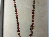 collier de perles en verre marron, présenté dans une boîte posée sur un fond blanc