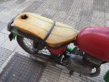 a red motorcycle with a wooden seat on the street