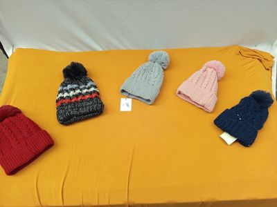 Plusieurs bonnets tricotés sont posés sur une nappe jaune