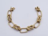 a close up of a gold chain bracelet on a white surface