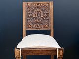 an old wooden chair with tassels on it in front of a black wall