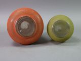two orange and green vases sitting next to each other