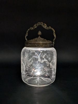 un bocal en verre ancien muni d'un couvercle et d'une poignée en métal