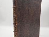an old book with a brown cover sitting on top of a white surface