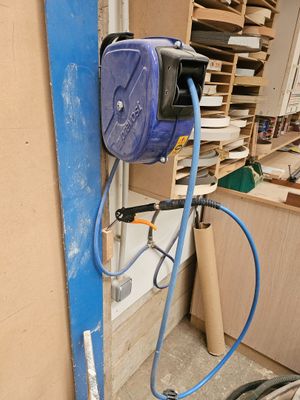 un tuyau bleu fixé au mur, à côté d'un tas de bois