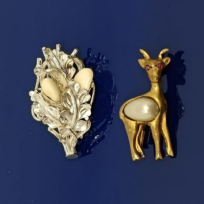 deux broches sur un fond bleu : l'une représente un cerf et l'autre un cerf