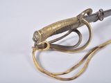 a gold colored sword with a red handle on a white surface