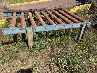 a rusted metal bed in the grass by the road