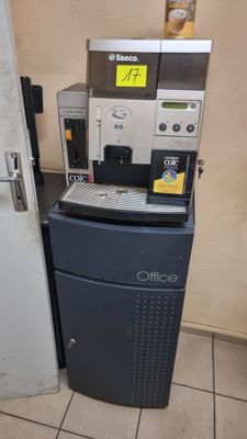 une machine à café posée à côté d'un réfrigérateur dans une pièce