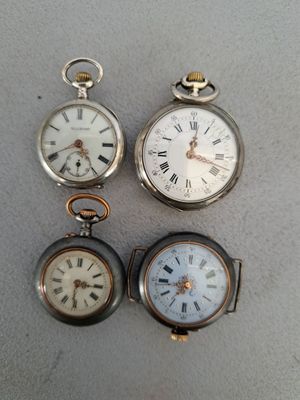 trois montres de poche différentes posées sur une table