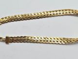 un bracelet à chaîne en or avec un fermoir sur fond blanc