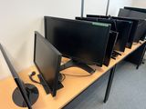 four computer monitors sitting on a desk in a room