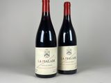 two bottles of red wine sitting next to each other on a table