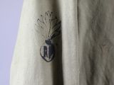 the back of a khaki jacket with a black and white logo on it