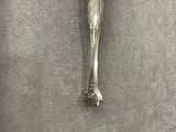 a silver spoon with a handle on a gray surface