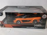 an orange toy car is in a box on a white surface