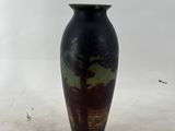 a black vase with a tree on it sitting on a white surface