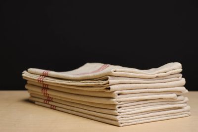 stack of folded linens on a wooden table against a black background