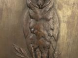 a bronze owl sitting on a branch of a tree