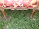 a red and gold upholstered bench in the grass