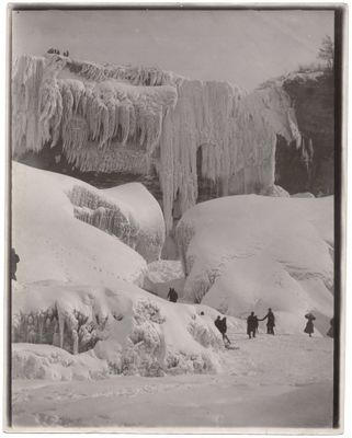 photographie en noir et blanc d'un groupe de personnes marchant dans une montagne enneigée