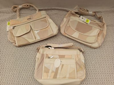 trois sacs à main beiges posés les uns à côté des autres sur un lit