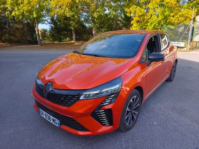 une voiture rouge garée sur un parking, avec des arbres en arrière-plan