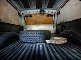 a tire in the back of a truck with a roll of tape on the bed