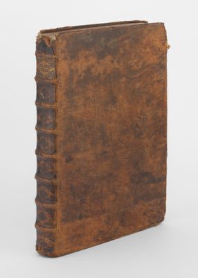 un vieux livre à la couverture brune posé sur une surface blanche