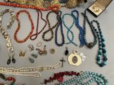 many different necklaces and bracelets laid out on a table