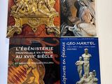 trois livres posés sur une table blanche, avec une horloge et une statue