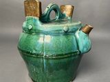 a green teapot with a wooden handle on a table
