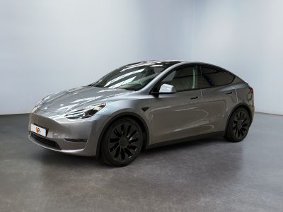 une Tesla Model Y argentée garée dans une pièce blanche