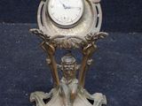 a small clock on a stand next to a coin