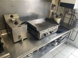 plan de travail en acier inoxydable dans une cuisine professionnelle équipée de deux friteuses et d'une cuisinière