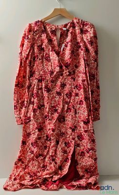 red floral dress hanging on a hanger against a white wall