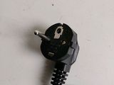 a black power cord plugged into a white wall