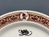 une assiette blanche avec une bordure marron et un motif floral