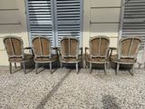 four chairs are lined up in front of a window with shutters