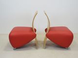 pair of red leather chairs with curved legs and a curved back