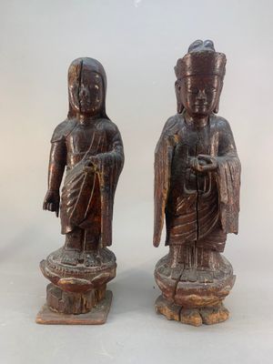 paire de statuettes asiatiques en bois sculpté représentant des bouddhas, posées sur des socles