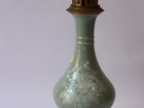 a green vase on a gold stand with a white background