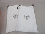 two white bags with a logo on them on a bed