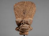 an old wooden mask on a stand with a gray background